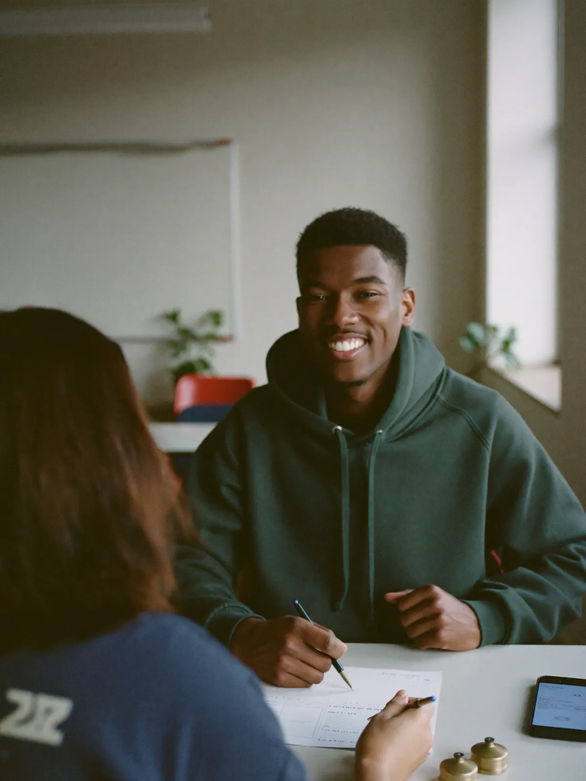 A young adult smiling during a one-on-one money coaching session, a budget worksheet on the table